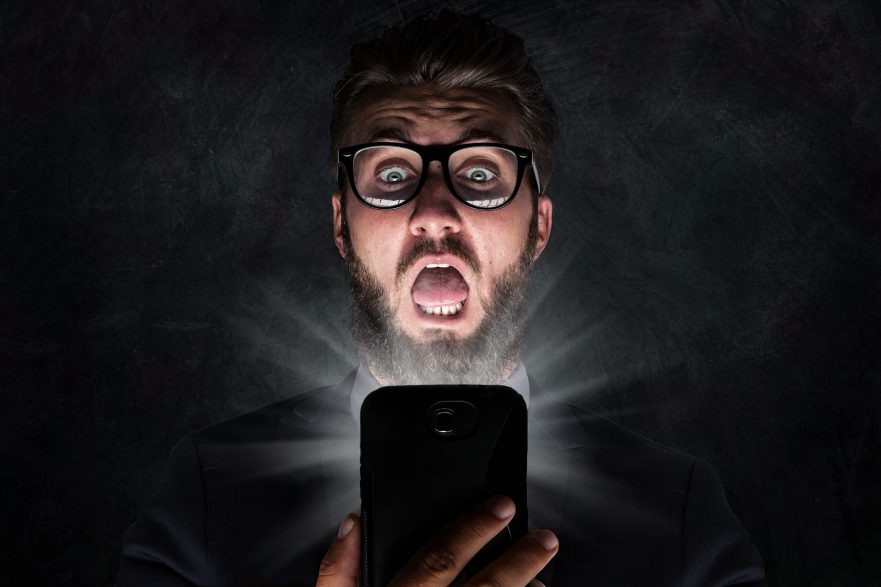 Nerd with glasses is shocked after reading news on his phone